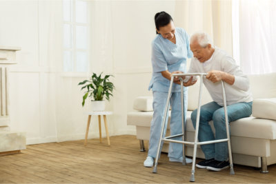 Caregiver assisting the elder man to stand